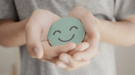 Person holding circle with smiling face