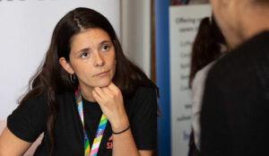 Young Woman Listening intently to a young man talking, her hand on her chin.